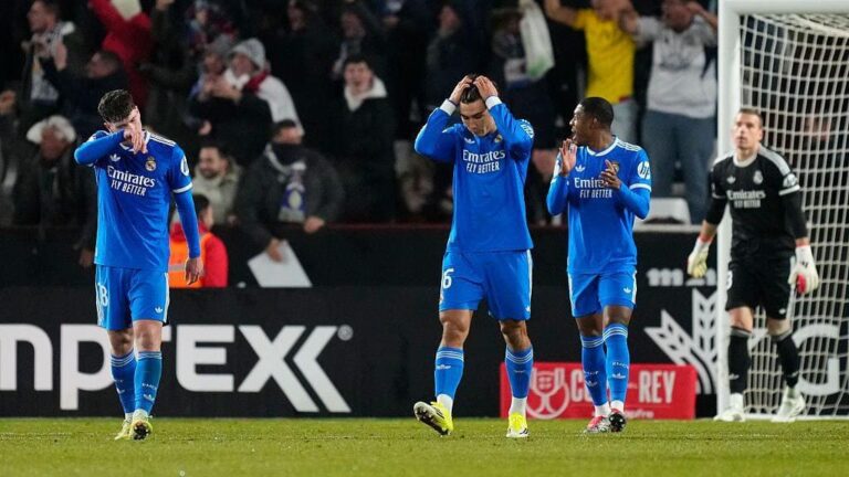 Three Real Madrid players in blue jerseys—likely Arda Güler (6), Dean Huijsen, and another—looking dejected near the goal after Albacete's 3-2 win in Copa del Rey Round of 16 at Estadio Carlos Belmonte, with crowd and Albacete goalkeeper in background.